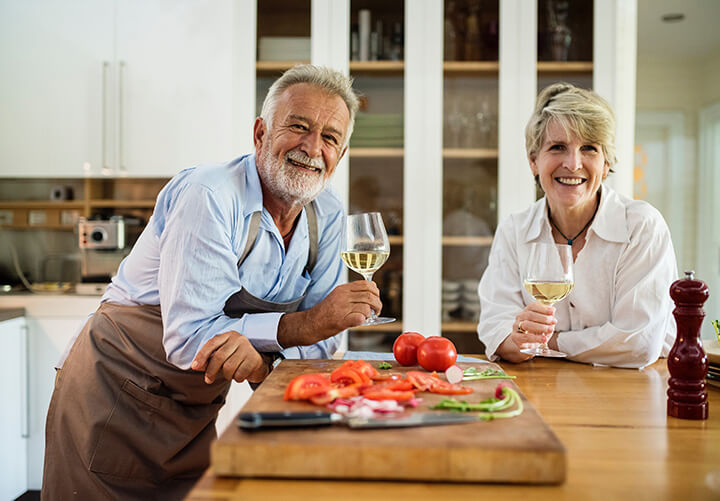 Two elderly people enjoying some cooking and wine
